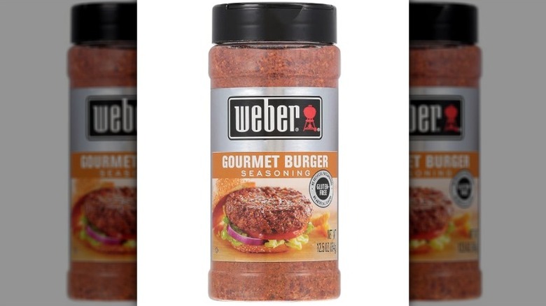 Isolated on a white background is a container of Weber Gourmet Burger Seasoning