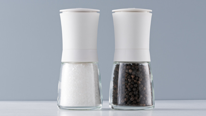 Closeup of salt and pepper grinders isolated on a blue and white background