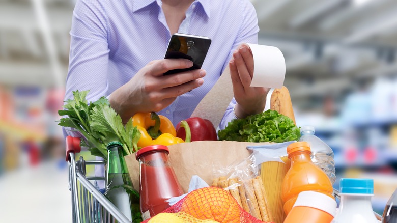 Person pushing cart, holding phone