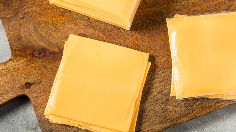 Stacks of American cheese singles on a wooden board