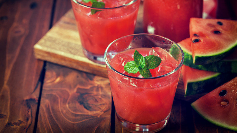 Two watermelon drinks with mint garnish and slices of watermelon