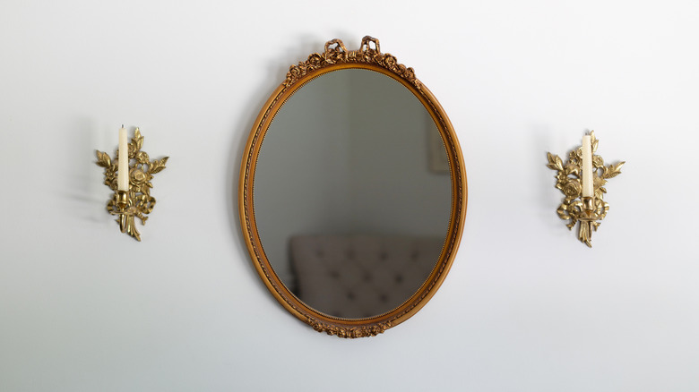 A mirror with a small bow on top of it on a white wall