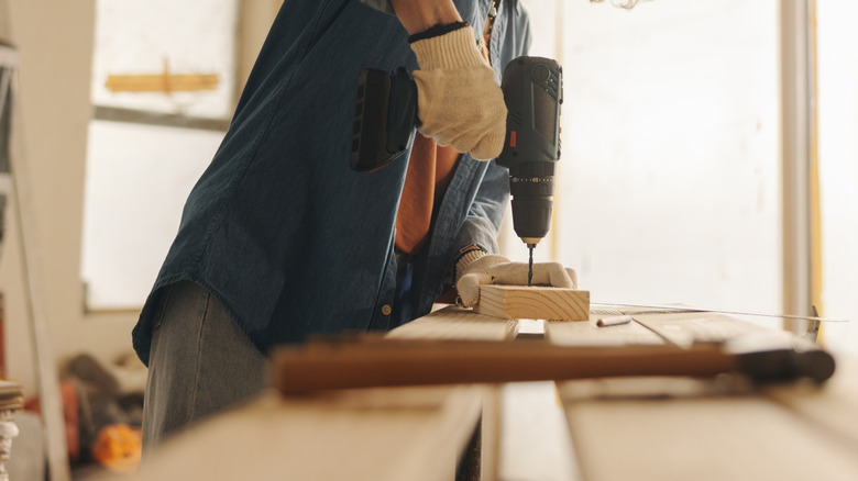 A person works on renovating their kitchen with a drill and wood
