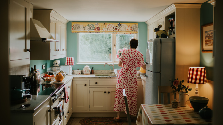 A woman is in a practical but pretty vintage styled kitchen