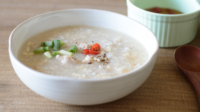 Bowl of chicken congee topped with chopped vegetables