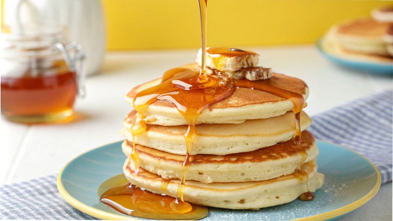Stack of pancakes, with syrup being poured on top