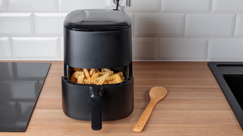 Black air fryer with fries in the basket