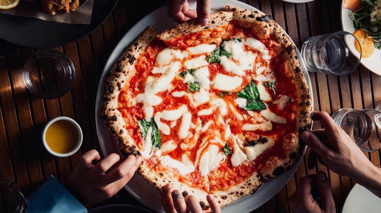 grabbing slices of margherita pizza