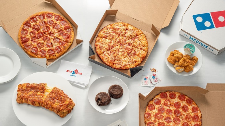 Assorted Domino's pizzas and sides on white surface