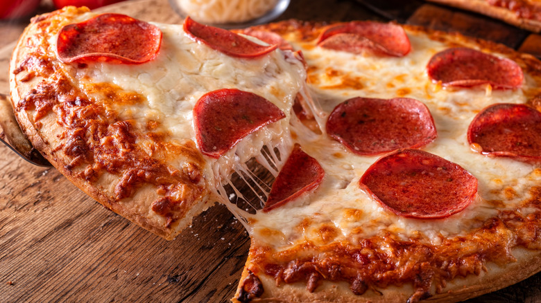 Spatula pulling slice of pizza away from pie