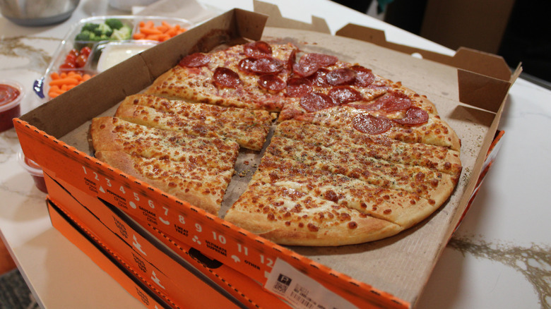 Little Caesars pizza and cheesy bread on stack of boxes