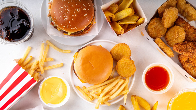 Various fast food items, sauces, and cola on a white counter