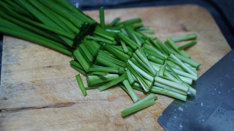 Freshly chopped garlic chives on a wooden cutting board