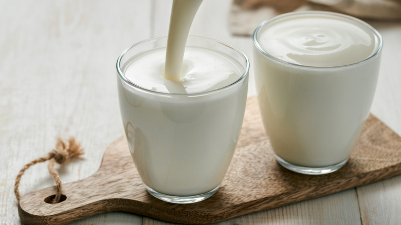 A person pouring buttermilk into a glass.