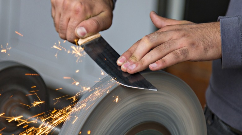Sparks fly as person sharpens knife on bench grinder