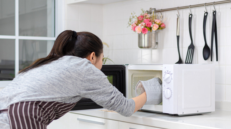Person grabbing food from microwave