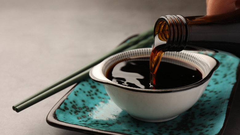 Pouring soy sauce into a bowl on gray table