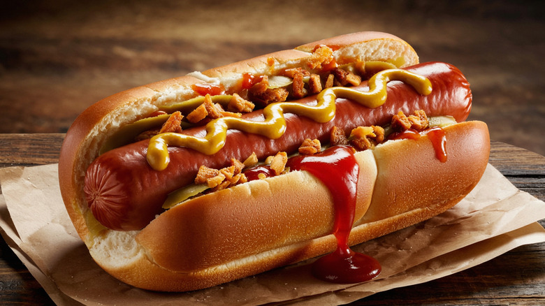 A hot dog in a bun with mustard, ketchup, and fried onions.