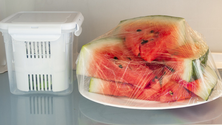 Watermelon wedges covered with plastic on fridge shelf