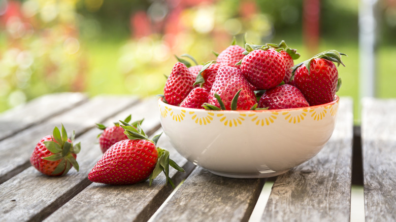 Fresh strawberries in bowl on wooden table