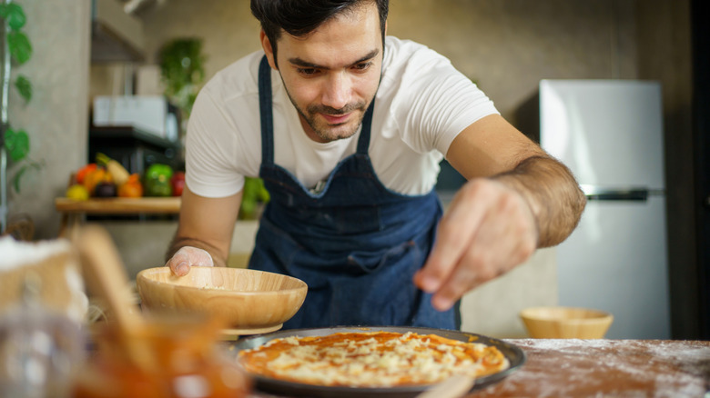Person making homemade pizza in the kitchen