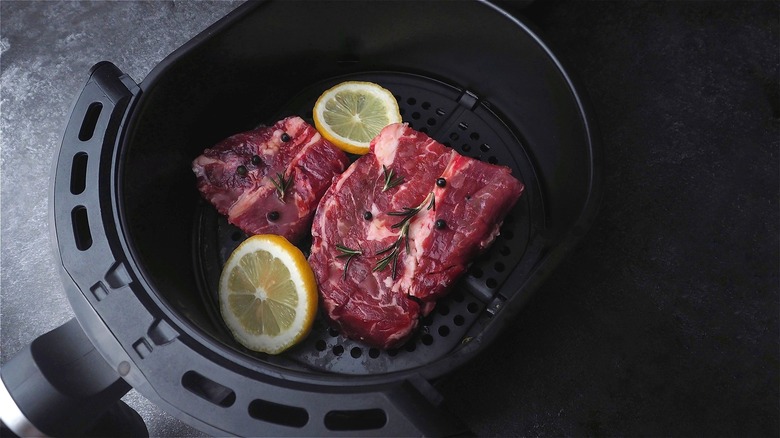 Raw steak in air fryer basket 