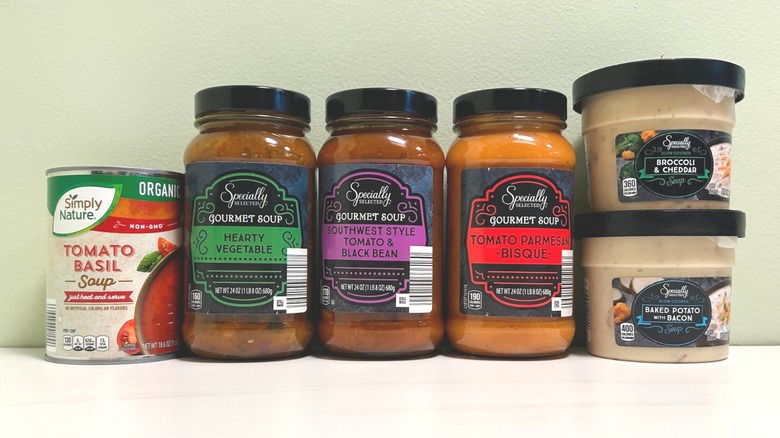 Six jars of Aldi-brand soups lined up with different flavors visible on the labels