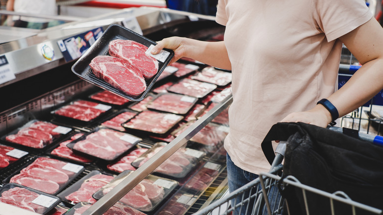 person holding pack of raw beef at grocery store