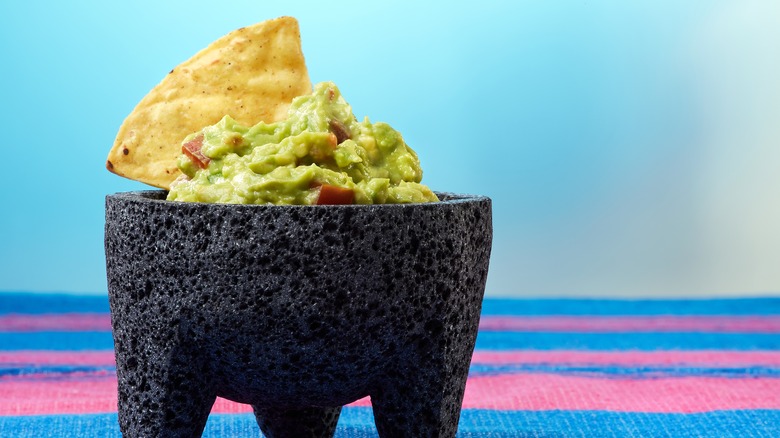 Guacamole in mortar, blue background