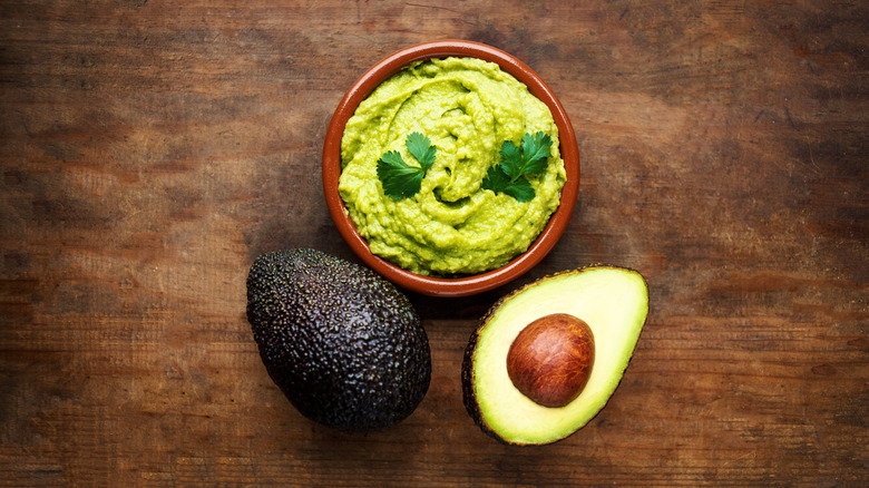 Guacamole and Hass avocado on wood