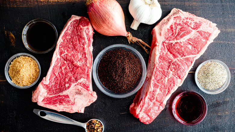 2 marbled steaks with a small bowl of coffee grounds and other spices for a rub