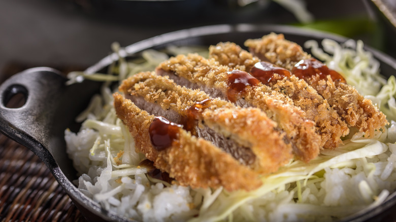 pork katsu in skillet over cabbage