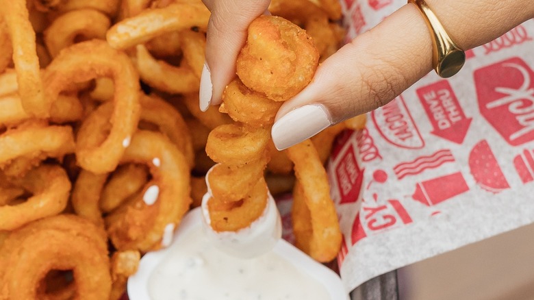 Fingers dipping fry into sauce