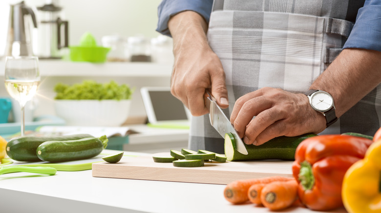 chef with wine chopping zucchini