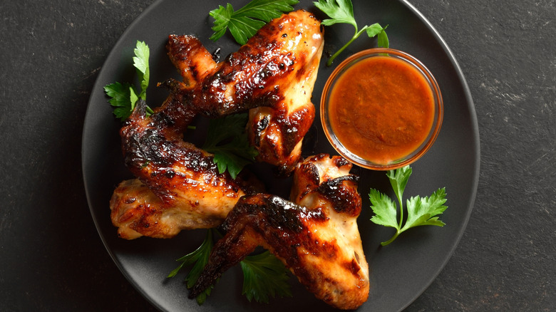 Barbecue chicken wings with sauce on black plate