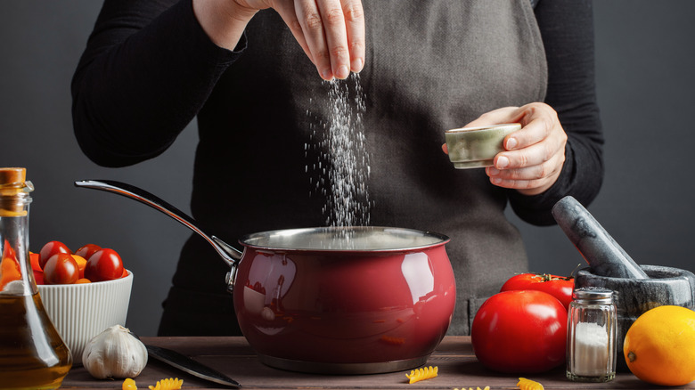 cook salting a pot of water