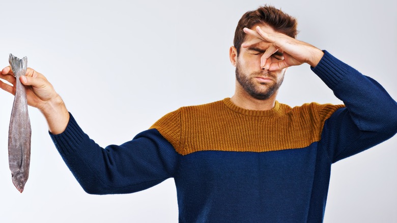 Man holding a smelly fish and plugging his nose