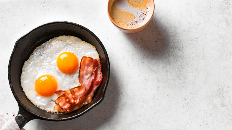 Two fried eggs in skillet with bacon