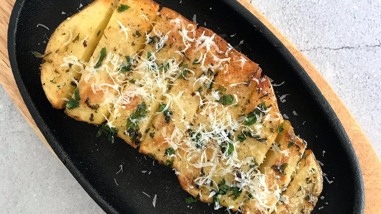 Large scored potato in cast iron pan