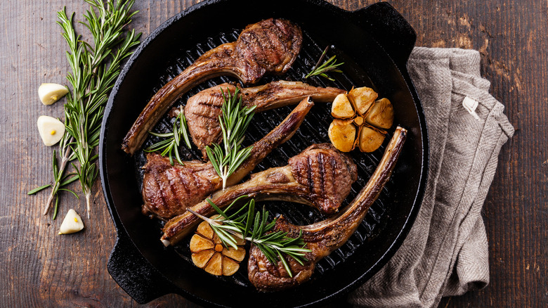 lamb chops in a cast iron pan cooked with garlic and rosemary