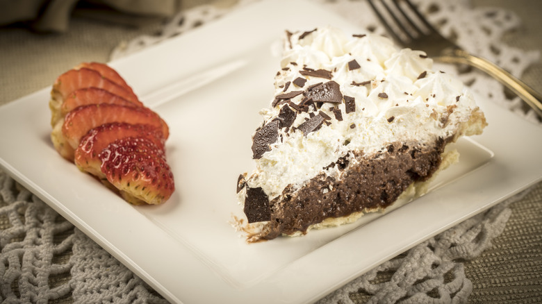 Chocolate cream pie and sliced strawberries on a plate