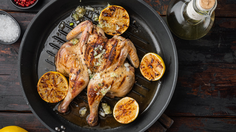 spatchcocked chicken in skillet, lemon
