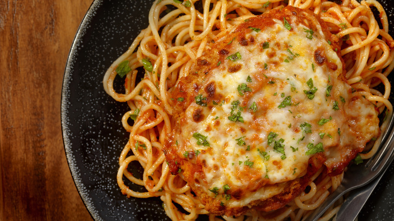 Top-down view of chicken parmesan on spaghetti, with oven-browned cheese on top