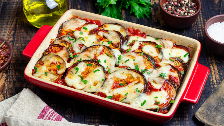 A ceramic baking dish with cooked eggplant parmesan topped with golden cheese