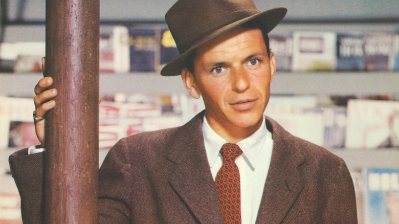 frank sinatra wearing brown suit and had holding onto wooden pole