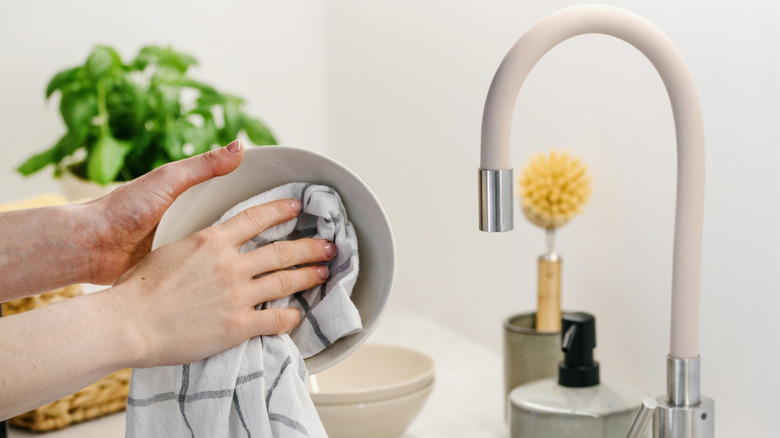 Two hands drying a bowl with a dish towel