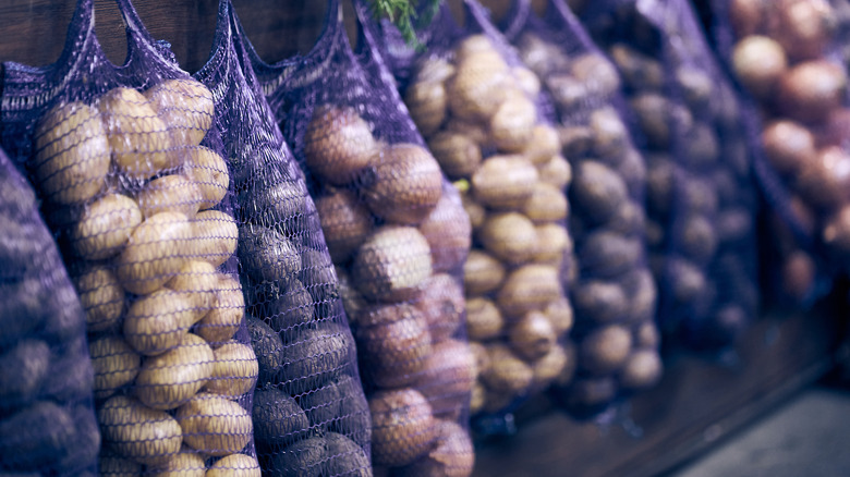 Purple mesh sacks of potatoes hanging at a market