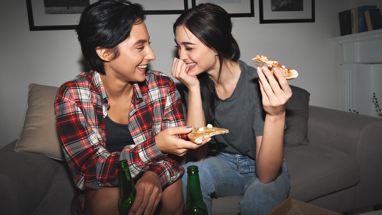 two girls eating pizza and laughing