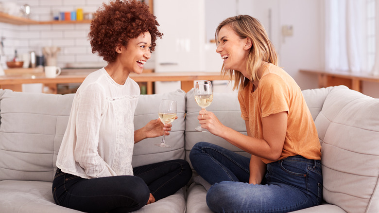 two women drinking wine on sofa