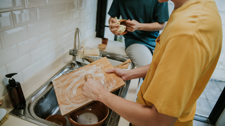 Person scrubbing wooden cutting board